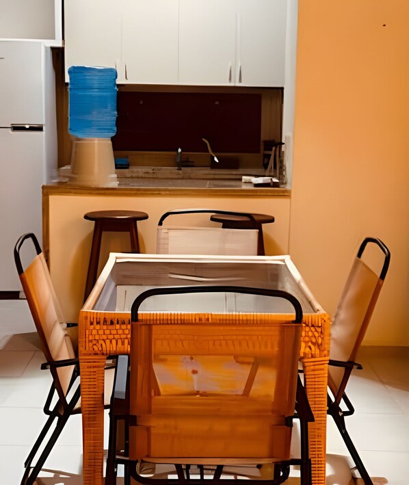 Une cuisine compacte avec des meubles blancs, une machine à café et une table à manger avec des chaises.