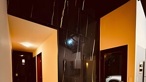 A modern hotel lobby with a dark marble wall, a glass door, and a tiled floor.