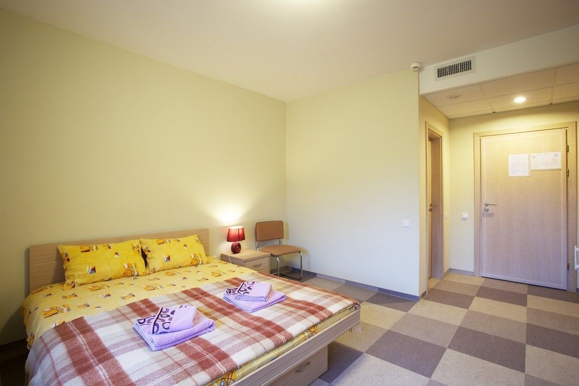 Ein Schlafzimmer mit Bett, Nachttisch, Lampe und Tür.