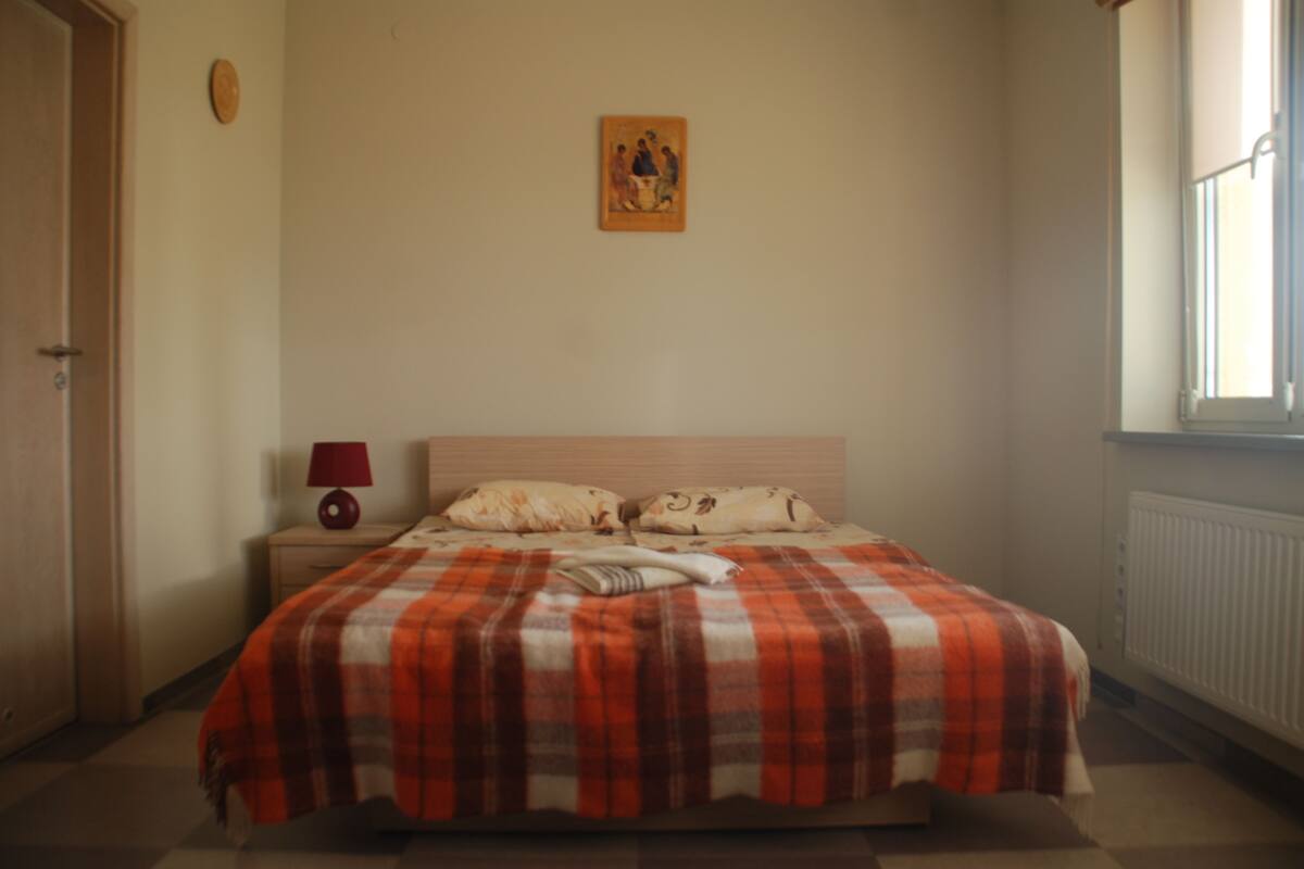 Une chambre à coucher avec un lit, une table de chevet, une lampe et un tableau accroché au mur.