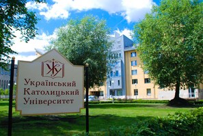 A sign for the Ukrainian Catholic University with a modern building in the background. - University Centre (Lviv)