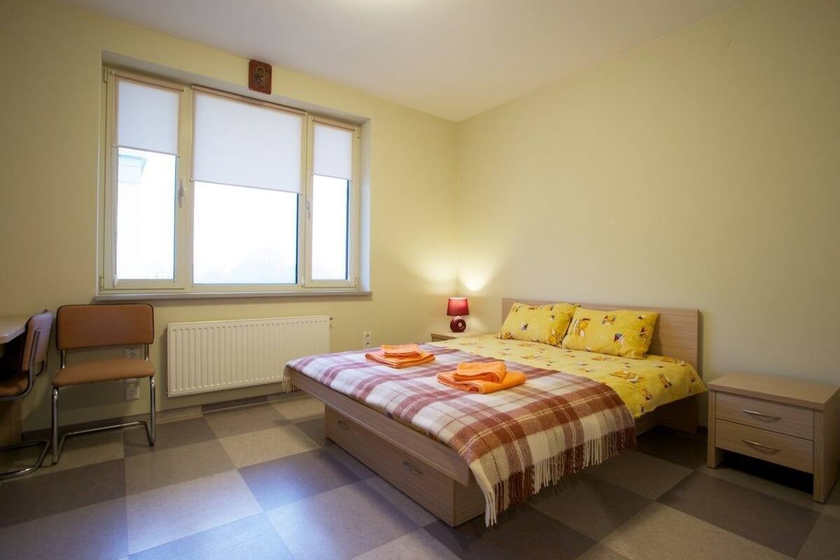 Une chambre à coucher avec un lit, une chaise, une table de chevet et une fenêtre.