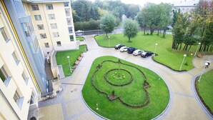 Un patio con césped circular, coches aparcados y un edificio de varios pisos.