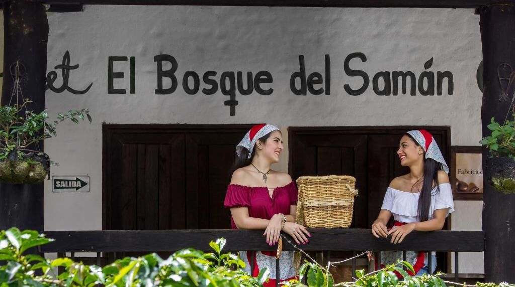 Een gebouw met een bord waarop 'El Bosque del Samán' staat en een bord dat 'UITGANG' aangeeft.