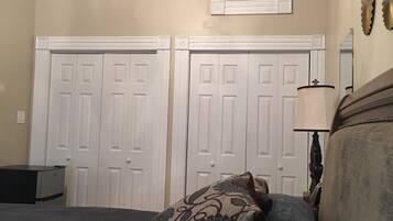A bedroom with a bed, two white doors, a ceiling fan, and a small desk.