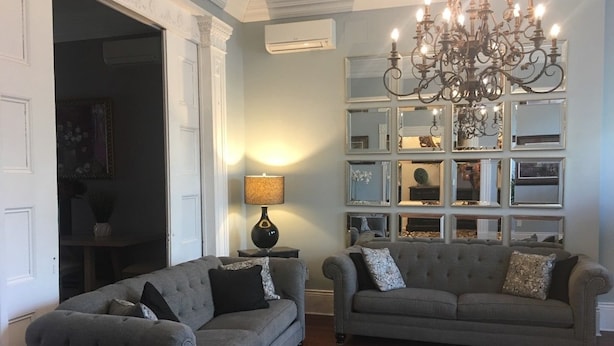 A living room with two grey sofas, a patterned rug, and a chandelier.
