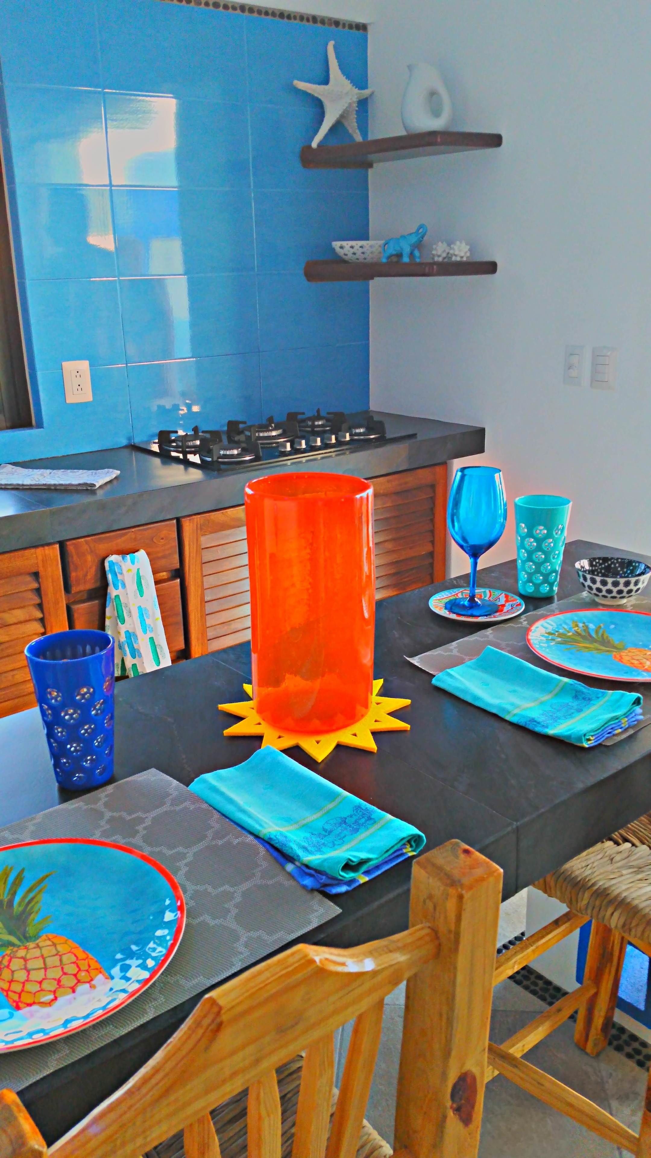 Una cocina con baldosas azules, estufa a gas y un mueble de madera.