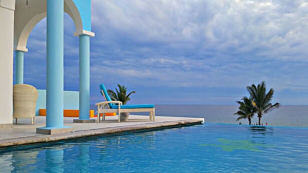 A poolside area with a lounge chair and a palm tree, overlooking a body of water. - Villa Star of the Sea - Adults Only (Isla Navidad)