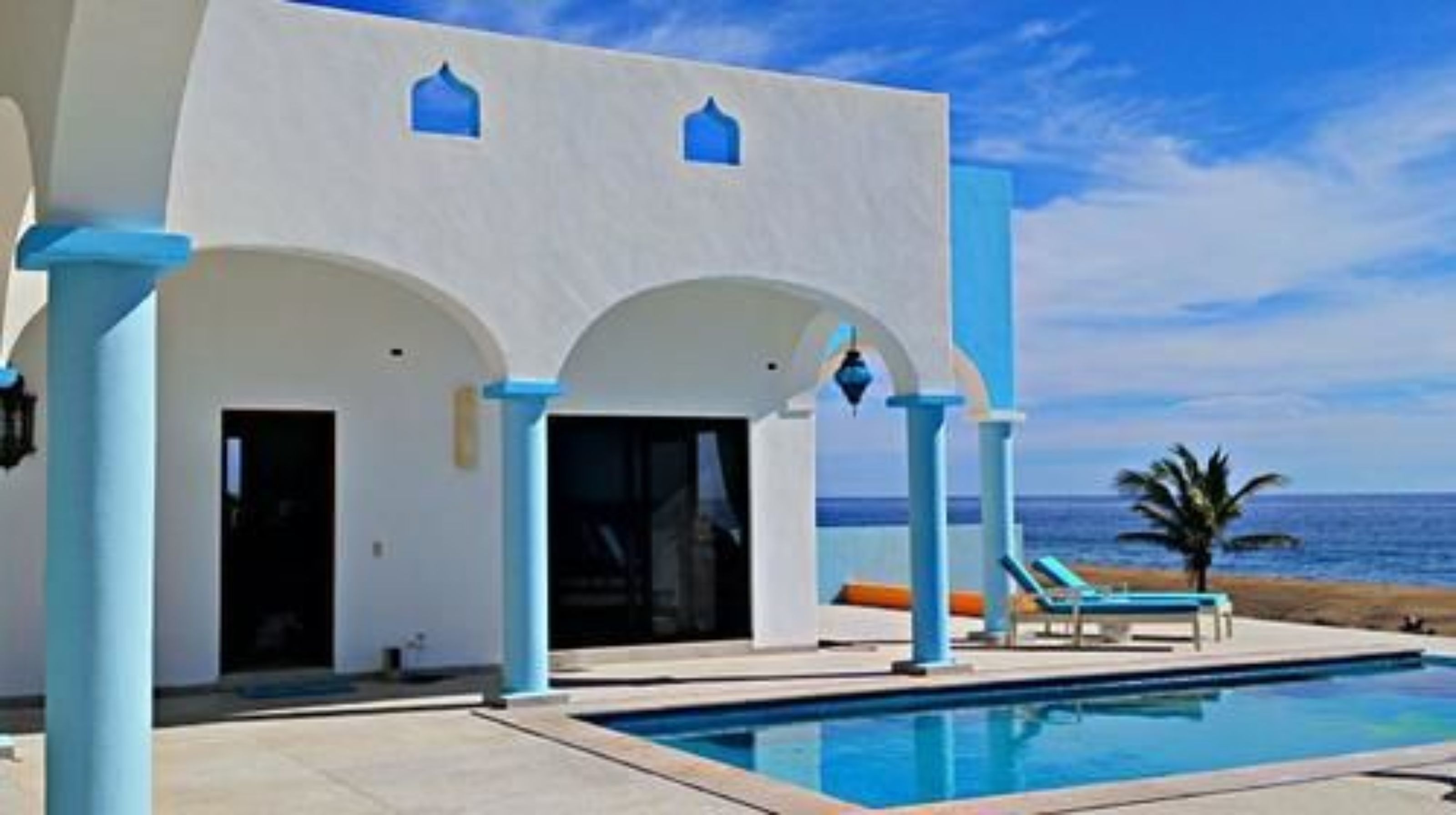 Un edificio moderno con piscina, que presenta arcos y vistas al océano.