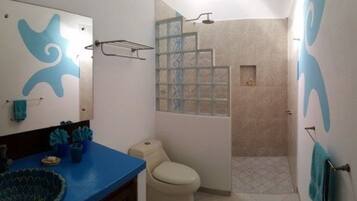 Un baño con encimera azul, inodoro, ducha con puerta de vidrio y espejo con diseño azul.