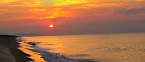 Atardecer sobre una playa, con el sol cercano al horizonte.