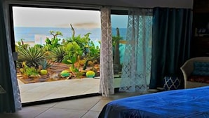 A room with a bed, a chair, and a view of the ocean through a sliding door. - Villa Star of the Sea - Adults Only (Isla Navidad)