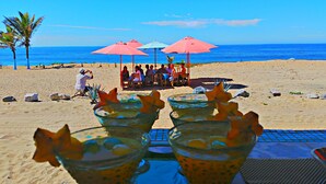 A beach scene with a table of drinks and umbrellas. - Villa Star of the Sea - Adults Only (Isla Navidad)