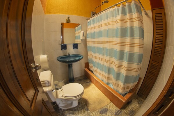 A bathroom with a toilet, sink, and shower curtain. - Euro Hostal - Hostel (Guatemala City)