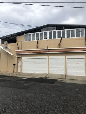 A two-story building with a beige facade, three white garage doors, and a flat roof. - Euro Hostal - Hostel (Guatemala City)