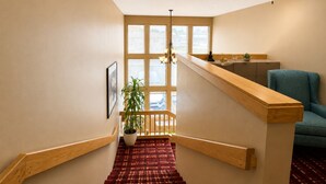 A staircase with a wooden handrail, a red patterned carpet, and a ceiling fan.