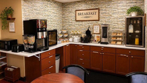 A breakfast bar with a stone wall backdrop, coffee machines, and a sign that reads 'BREAKFAST'.