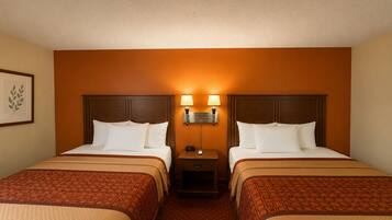 Una habitación de hotel con dos camas, una mesita de noche con lámpara y un cuadro en la pared.