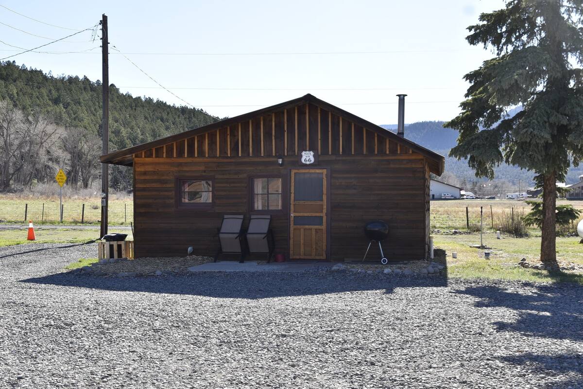 Une cabane en bois avec une cheminée, une porte et une fenêtre.