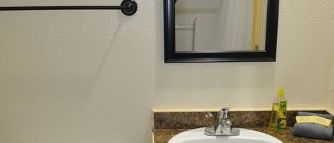 A bathroom with a toilet, sink, mirror, and wooden cabinet.