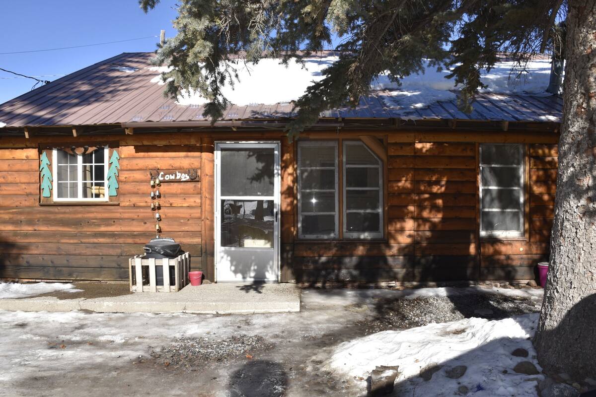 Une cabane en bois avec un toit en métal, une porte d’entrée et des fenêtres.