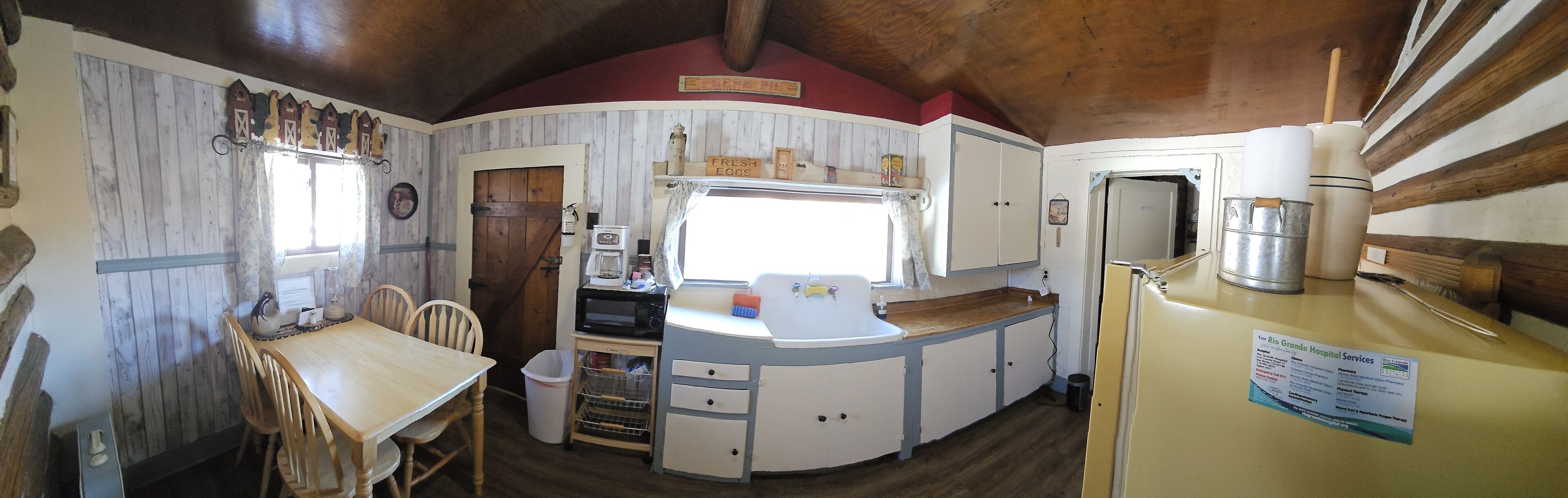 A compact kitchen with a wooden table and chairs, a sink, a microwave, and a refrigerator.
