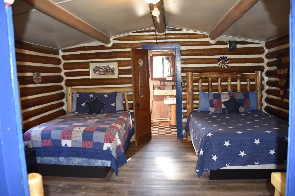 Une chambre de style rustique, avec deux lits, des murs en bois et un sol à carreaux.