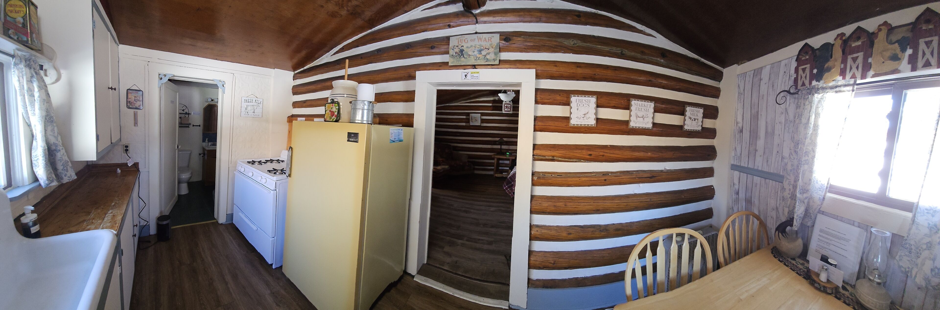 Una cocina rústica con paredes de madera, una estufa y un refrigerador.
