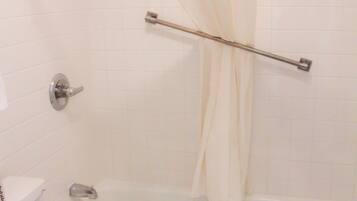 Une salle de bain avec des toilettes blanches, une baignoire et une pomme de douche.