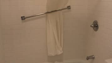 A bathroom with a bathtub, toilet, and a shower curtain.