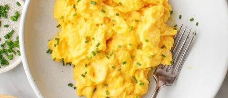 A bowl of scrambled eggs garnished with chives.