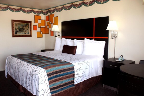 Quarto de hotel com cama, mesas de cabeceira, escrivaninha e uma cadeira.