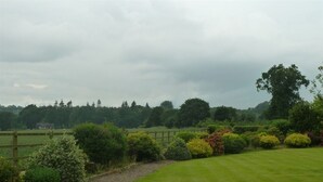 A well-maintained lawn with a wooden fence and various shrubs. - The Coach House (Stafford)