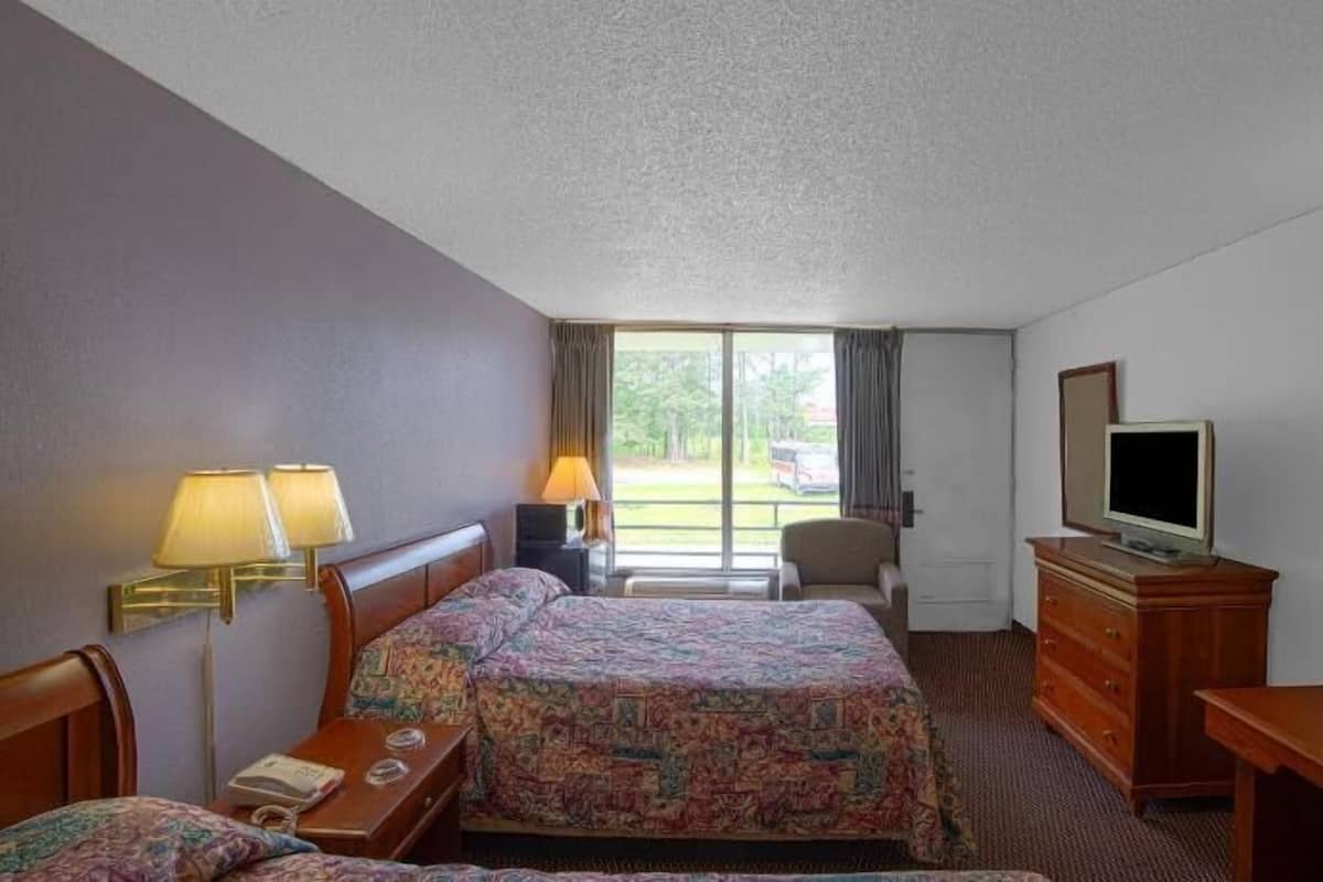 A hotel room with two beds, a television, a desk, and a chair.