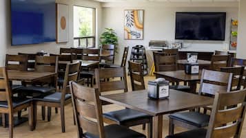 A conference room with multiple tables and chairs, a large flat-screen TV, and artwork on the walls.