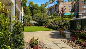 A courtyard with artificial grass, stone pathways, and various plants. - The Alcala Hotel Mission Valley/Seaworld (San Diego)
