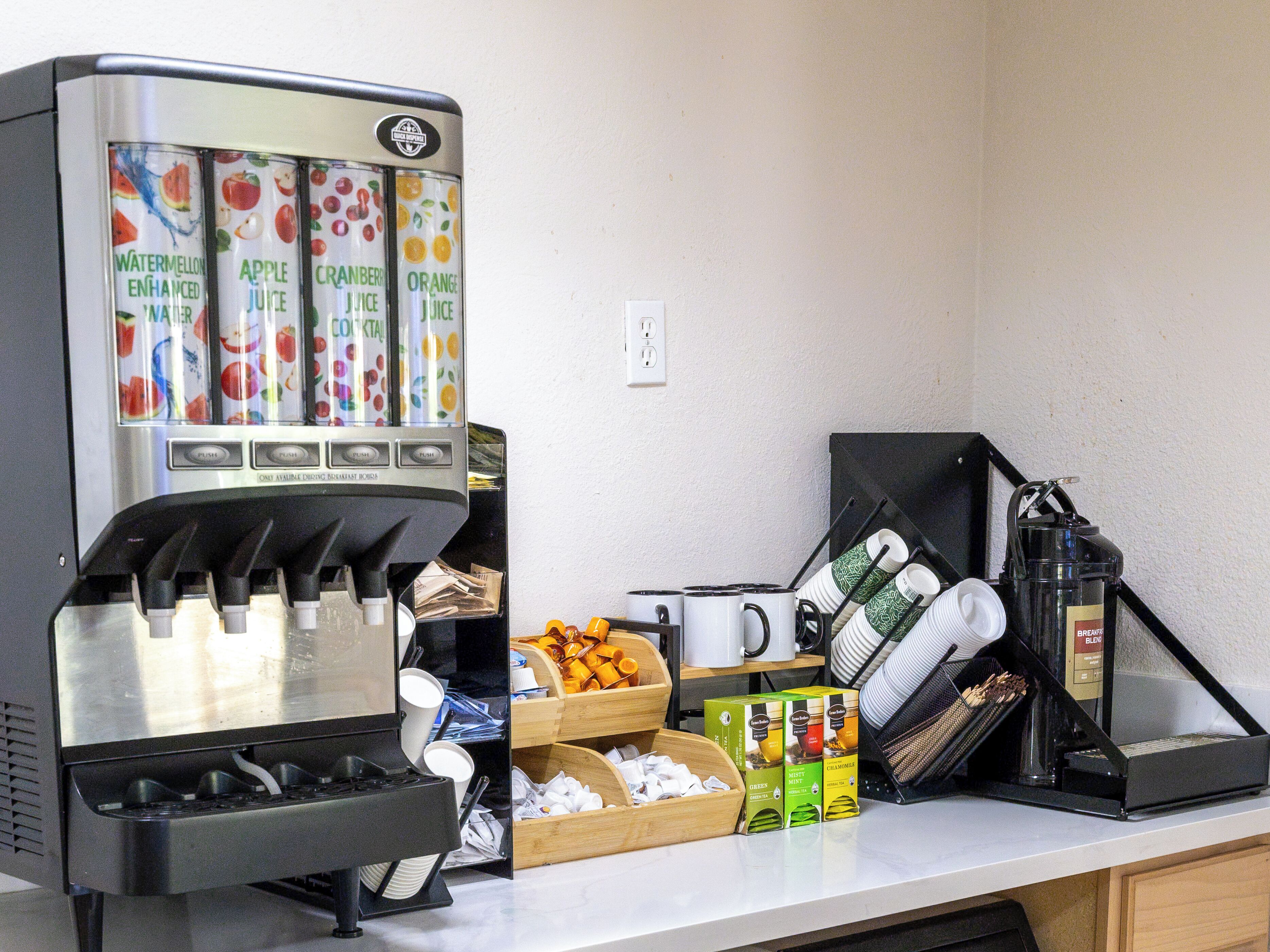 Una estación de café con dispensador de bebidas, cafetera y varios tipos de cápsulas de café.