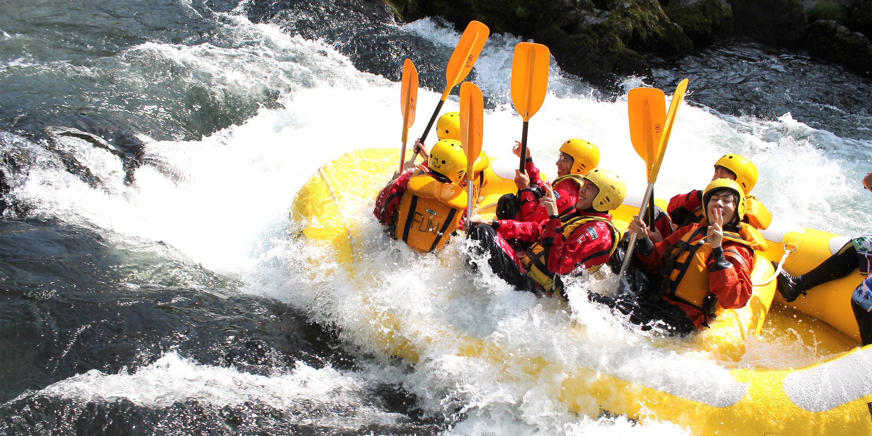 Een groep mensen in een gele raft die door een rivier met stromingen vaart.
