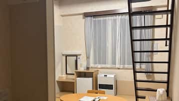 Habitación de hotel compacta con techo de madera, una mesa redonda para comer, una pequeña cocina y un ventanal con cortinas.