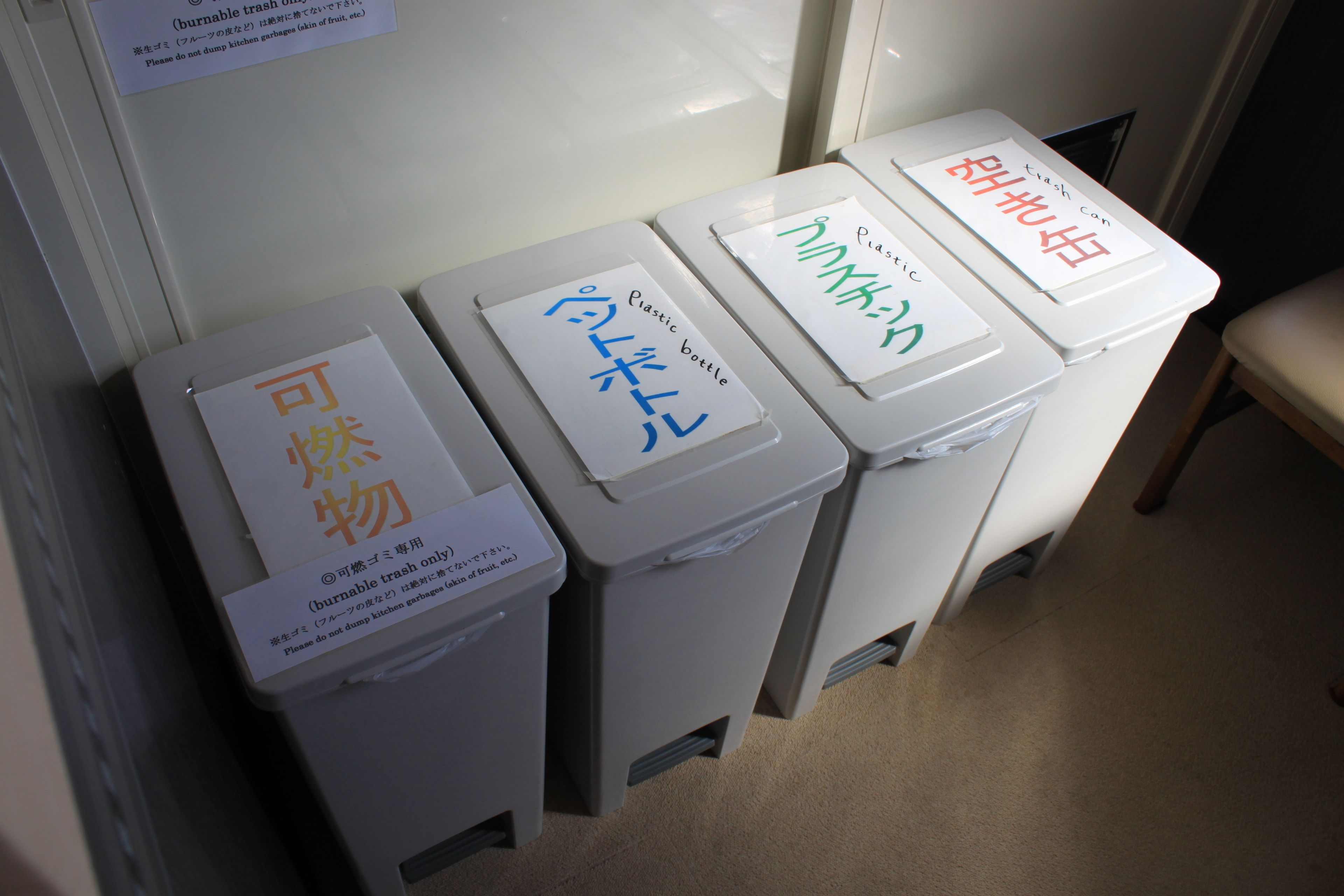 Three waste bins labeled for different types of trash, including plastic bottles, general waste, and food waste.