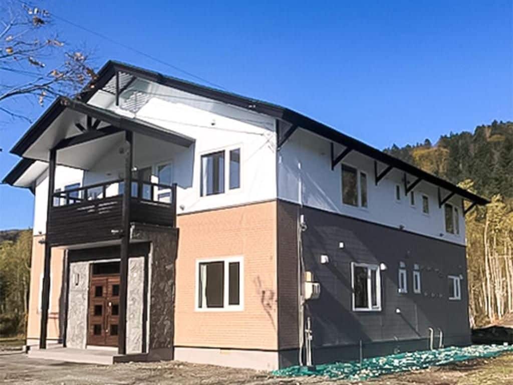 Un edificio de dos plantas con balcón, puerta principal y un pequeño porche.