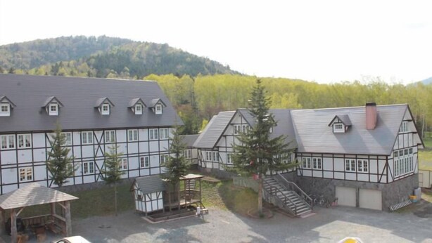 A traditional half-timbered building with a steep roof, a small wooden structure, and a staircase leading to a garage. - Petit Hotel Gracey Tomamu (Shimukappu)