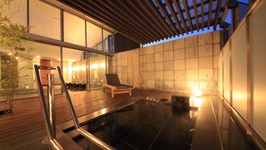 A modern outdoor hot tub area with a wooden deck, a lounge chair, and a glass-enclosed space. - Atami Tensui (Atami)