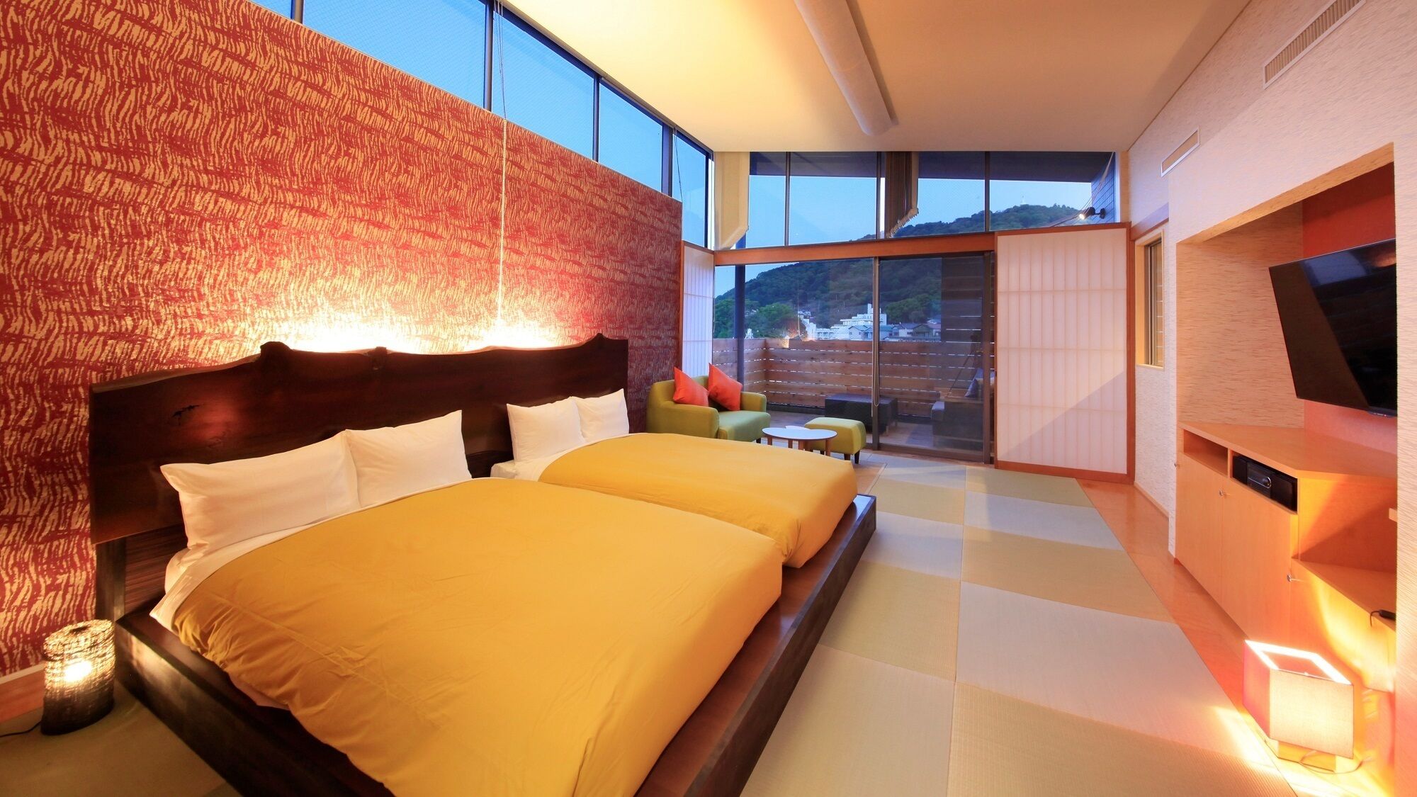 A modern hotel room with a large bed, a TV, and a balcony with a view.