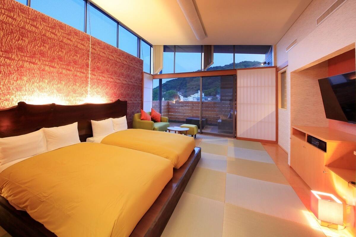 Una habitación de hotel moderna con una cama grande, televisión y balcón con vistas.