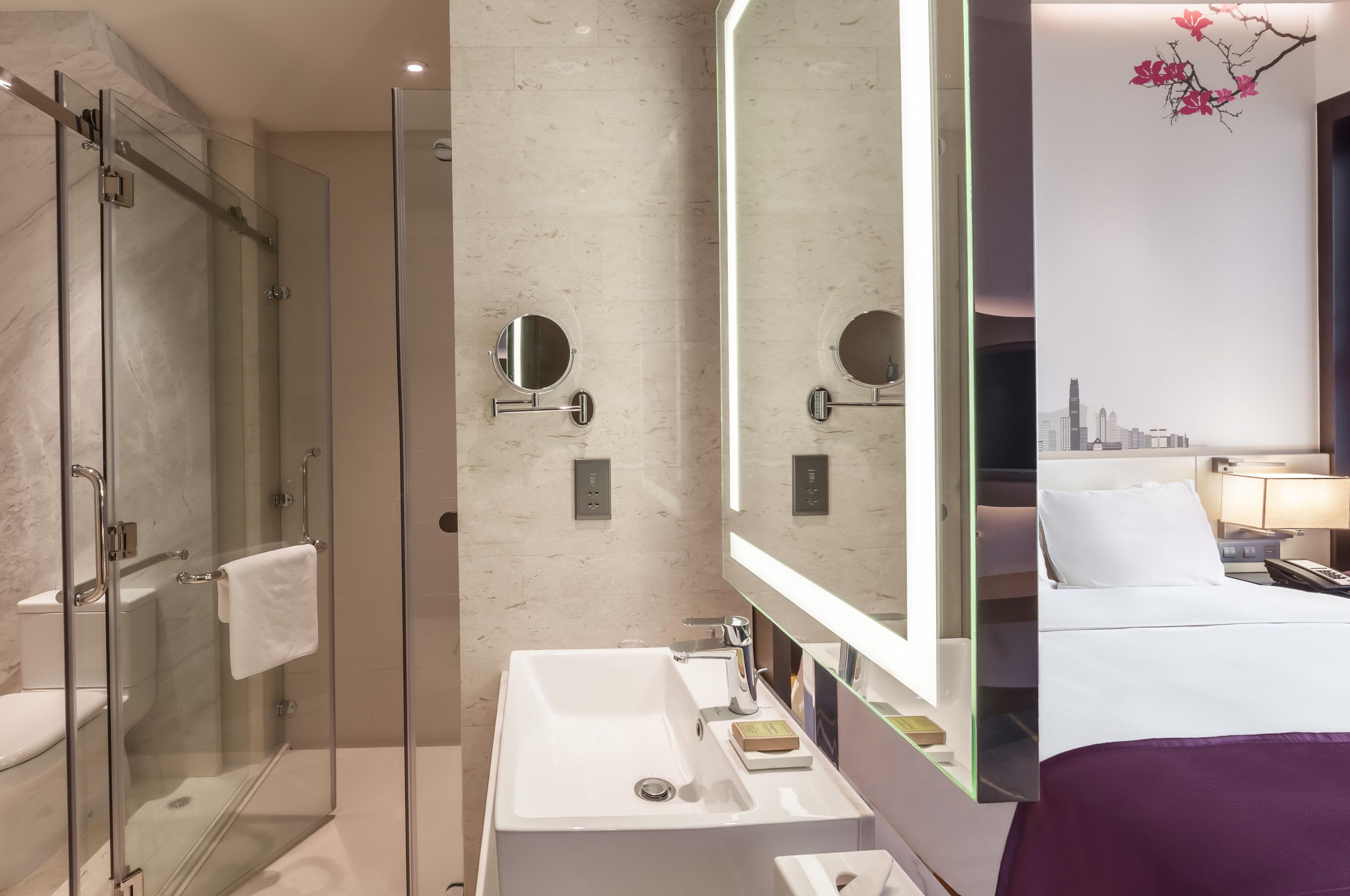 A modern bathroom with a glass shower enclosure, a large mirror, and a white sink.