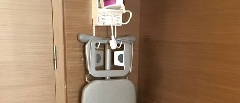 A compact, wall-mounted ironing station with a grey ironing board and a purple iron.