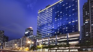 A modern hotel with a glass facade, multiple floors, and a prominent Hilton Garden Inn sign.