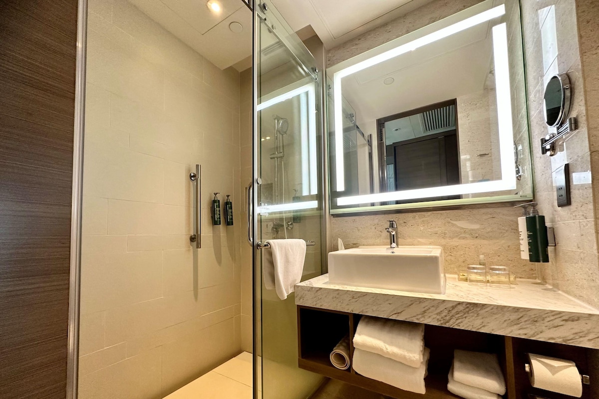 A modern bathroom with a glass shower enclosure, a white sink, and a large mirror.