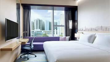A hotel room with a bed, a desk, a chair, a TV, and a large window with a city view.
